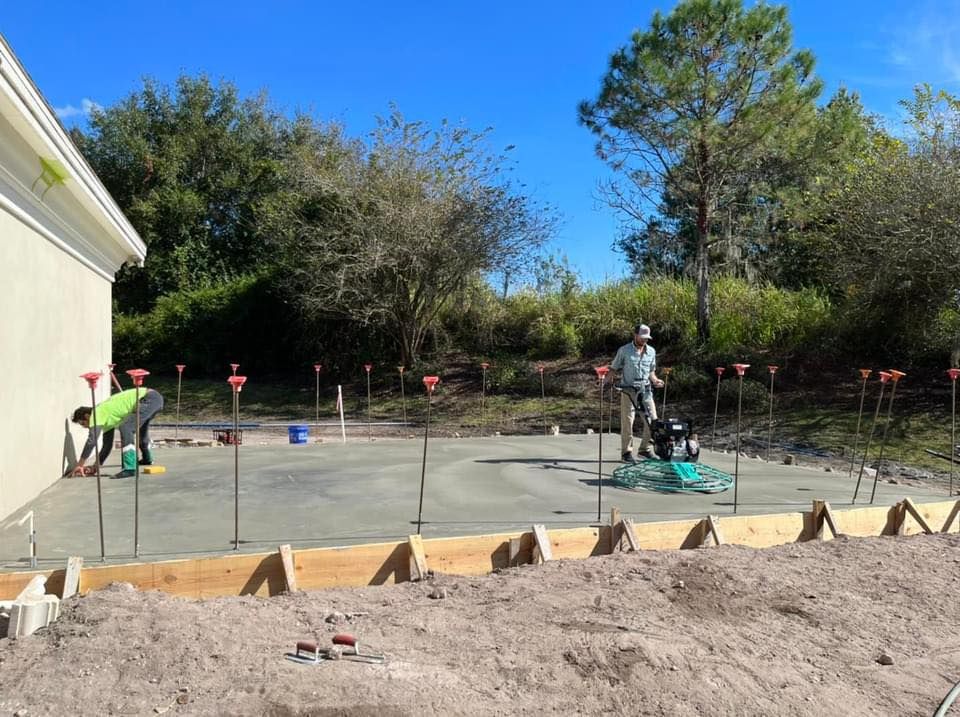 A group of construction workers are working on a concrete base for a house.