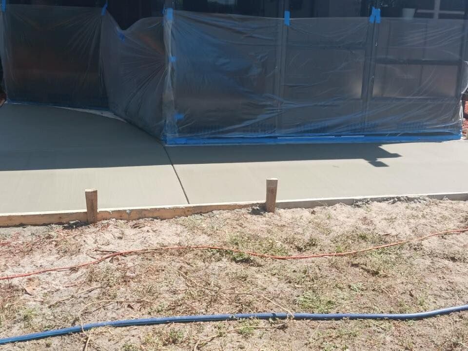 A concrete driveway is being built in a yard with a hose.