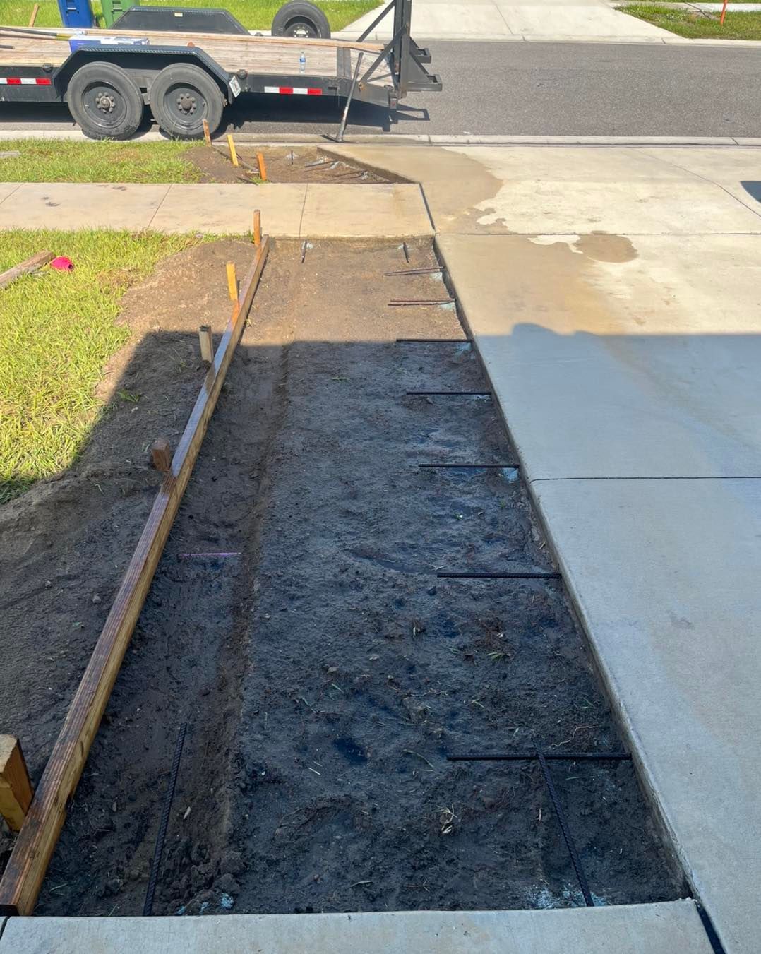 A concrete driveway is being built next to a trailer.