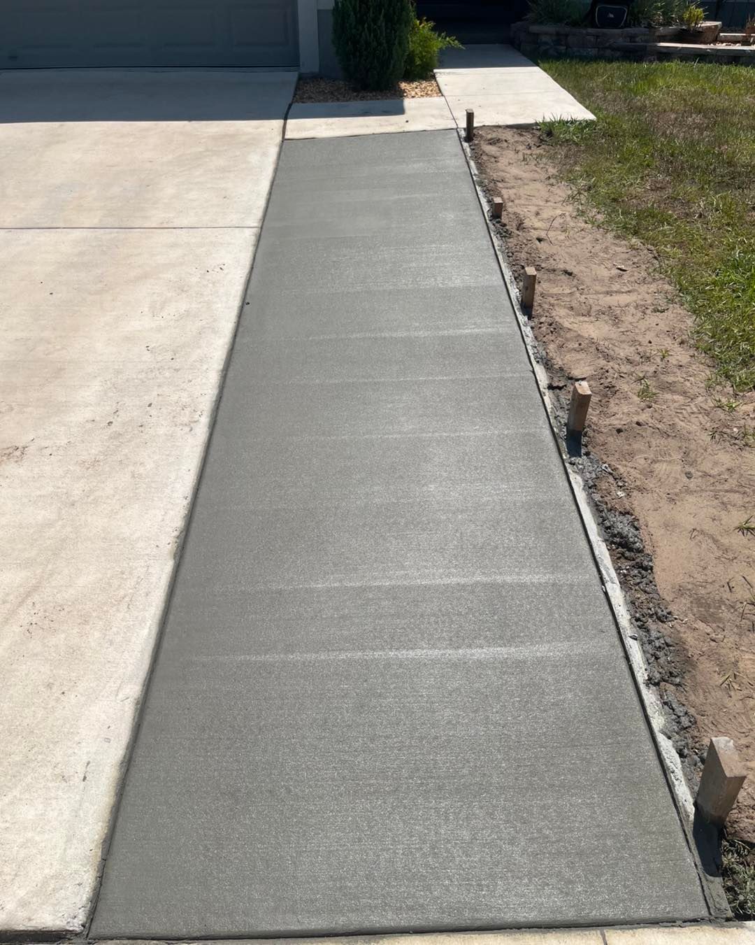 A concrete walkway is being built next to a driveway