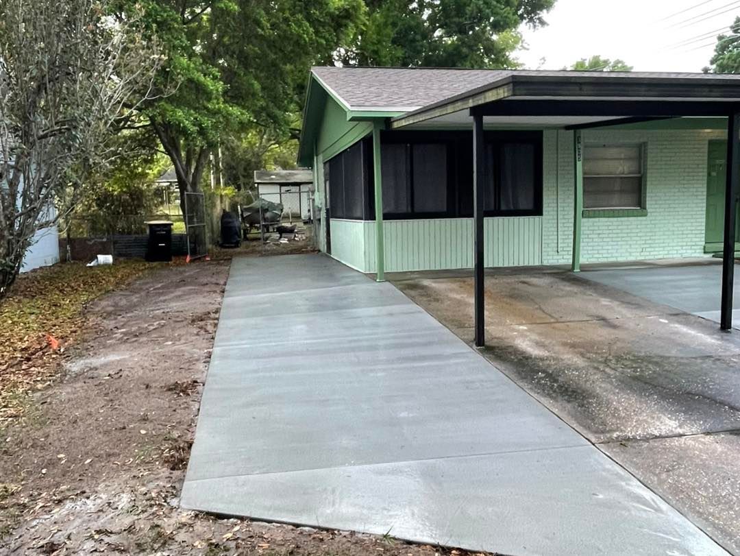 A concrete driveway leading to a house with a screened in porch.