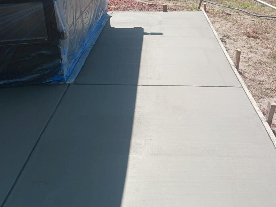 A concrete walkway is being built next to a building.