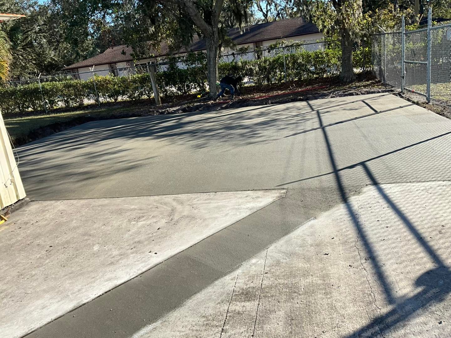 A shadow of a person is cast on a concrete driveway.