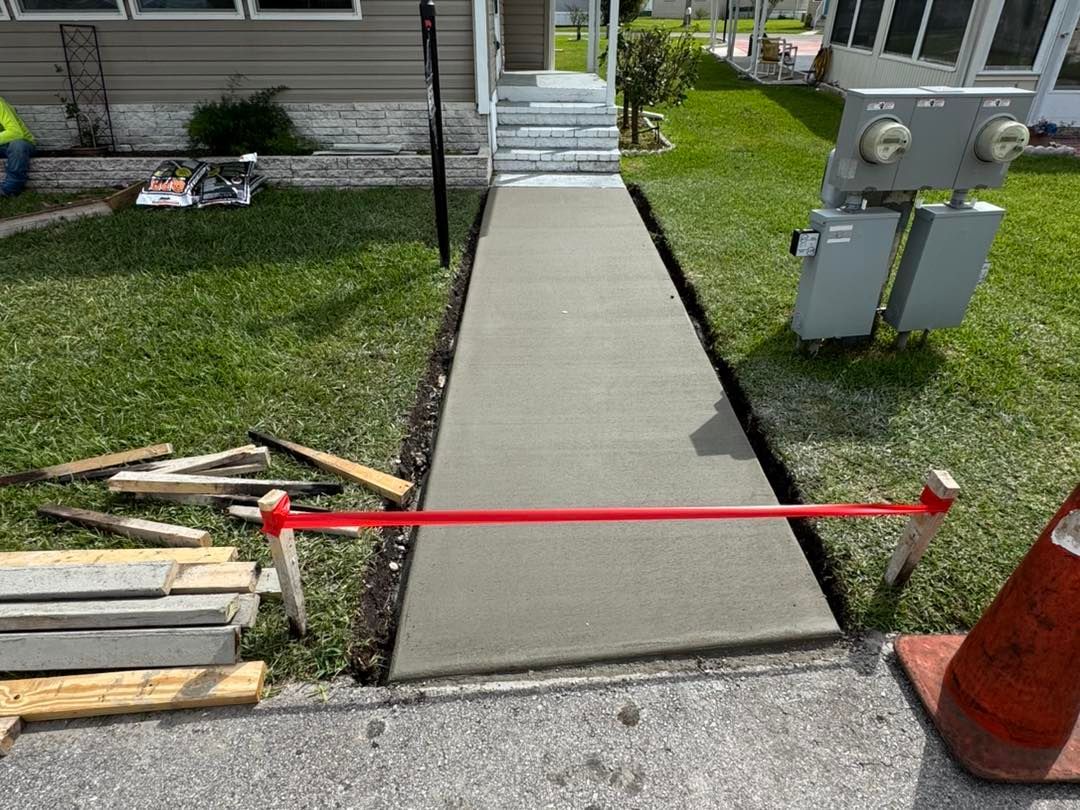 A concrete walkway is being built in front of a house.