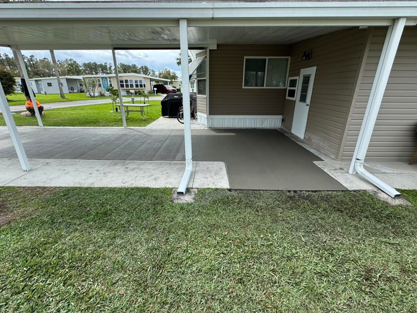 A house with a covered porch and a concrete walkway in front of it.