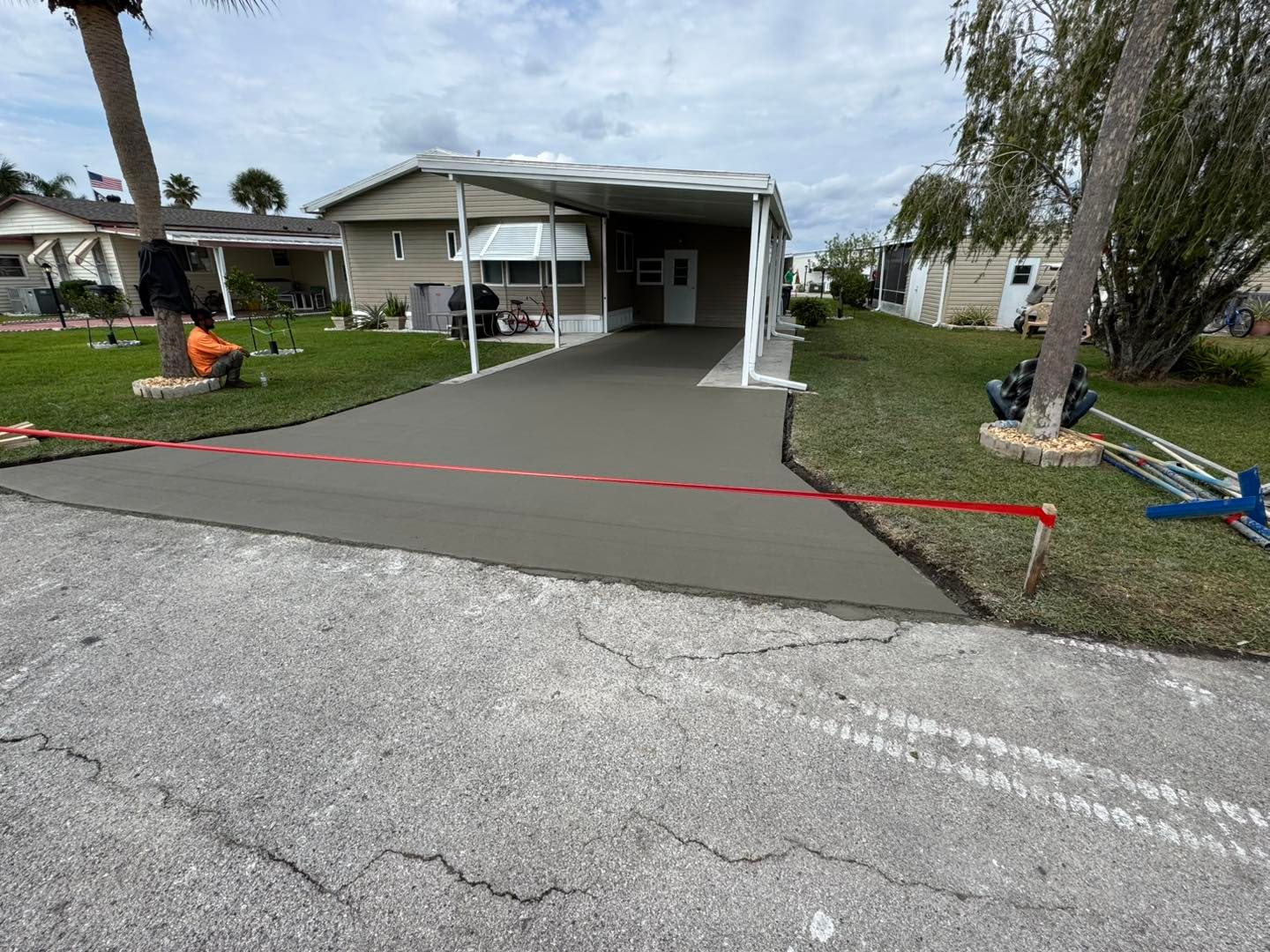 A concrete driveway is being built in front of a mobile home.