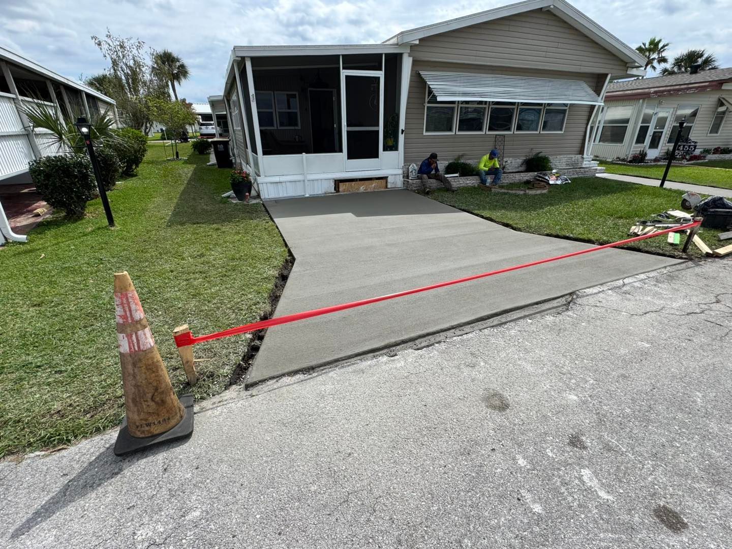 A concrete driveway is being built in front of a mobile home.