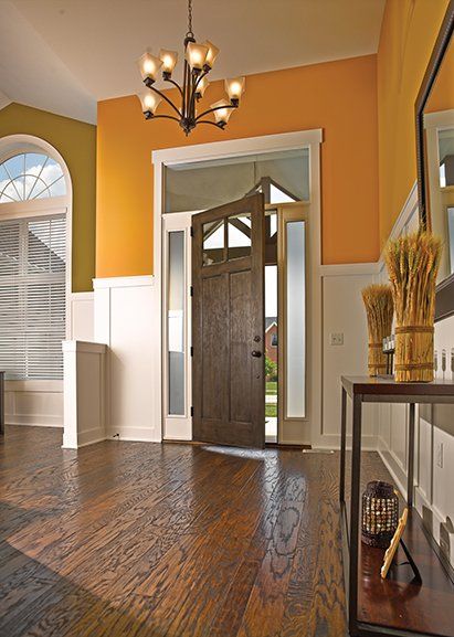 A hallway with a wooden floor and a chandelier hanging from the ceiling