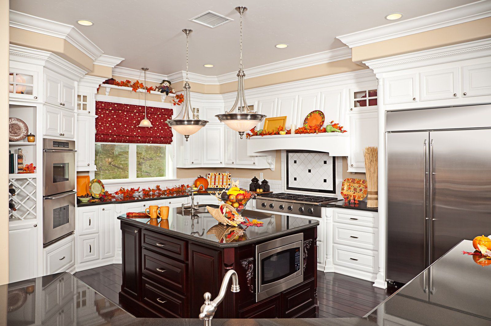 A kitchen with white cabinets and stainless steel appliances and a large island in the middle.