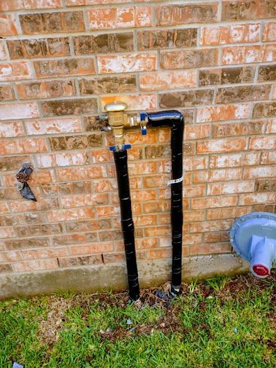 A black pipe is attached to a brick wall.