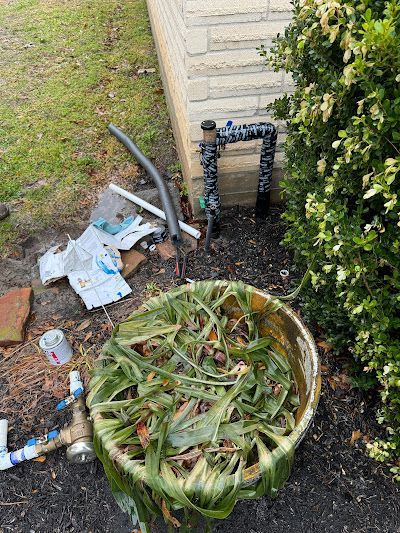 A bucket filled with leaves is sitting on the ground next to a pipe.