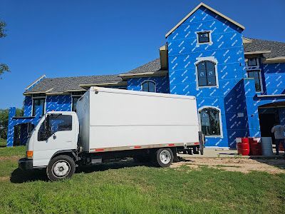 A white truck is parked in front of a large house under construction.