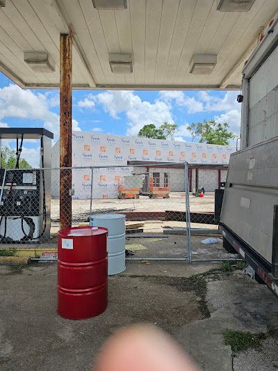 A red barrel is sitting under a gas station roof.