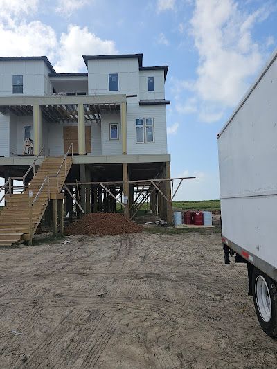 A white truck is parked in front of a house under construction.