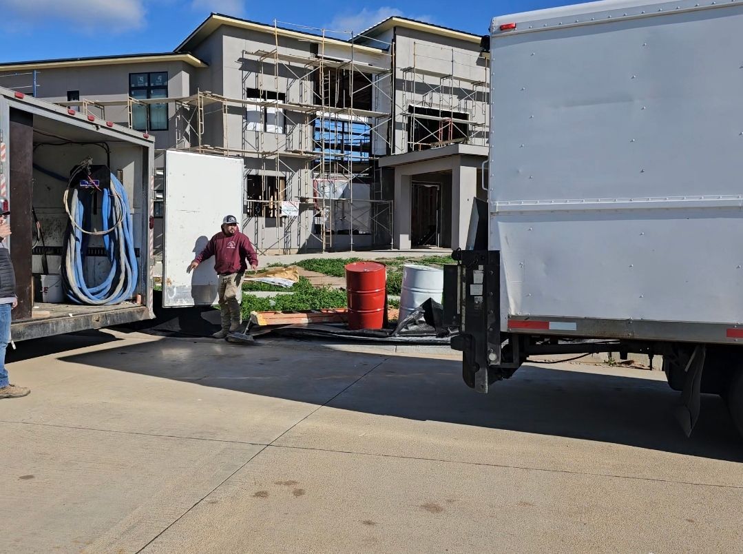 A man is loading a white truck in front of a house under construction.