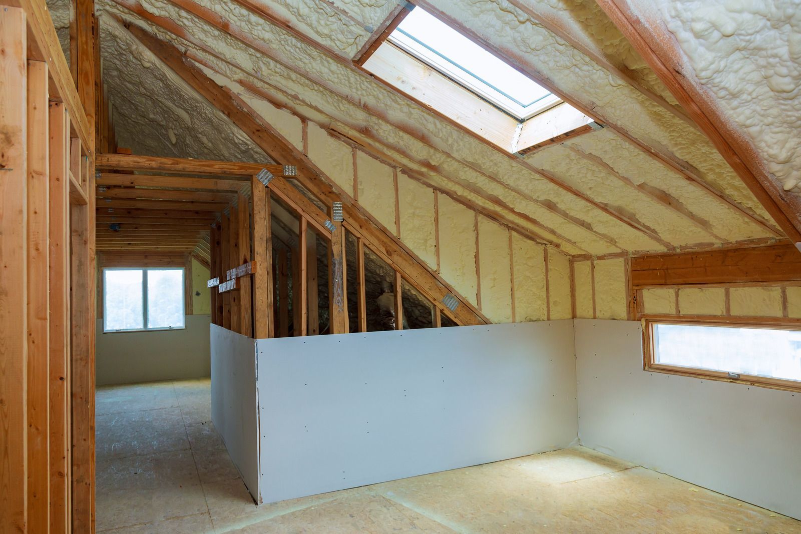 A room in a house under construction with a skylight in the ceiling.