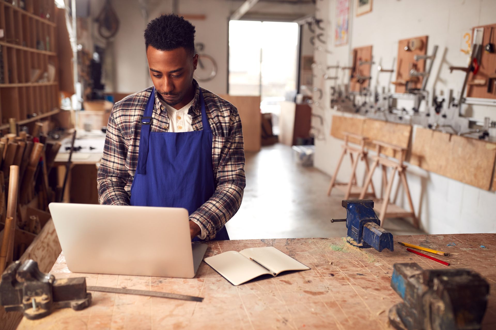 A man is using a laptop computer in a workshop.