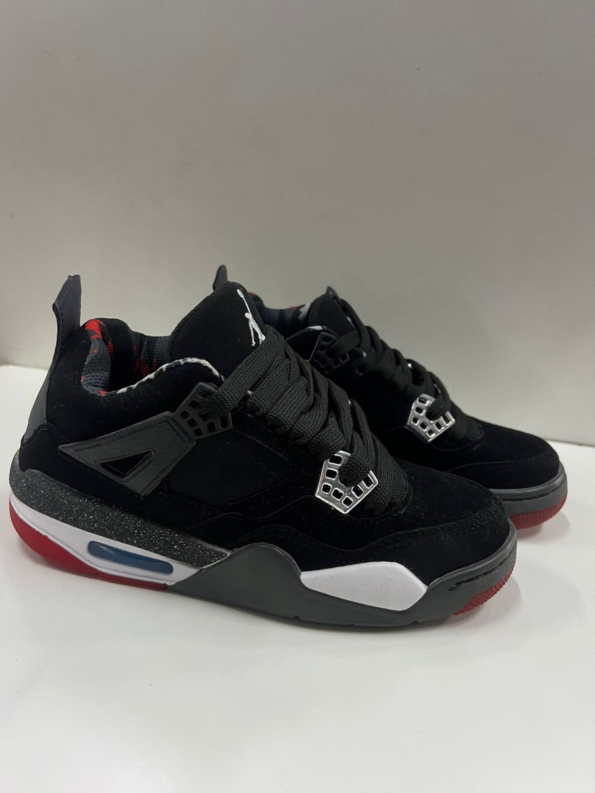 Zapatillas Air Jordan 4 negras y rojas con detalles en blanco y gris.