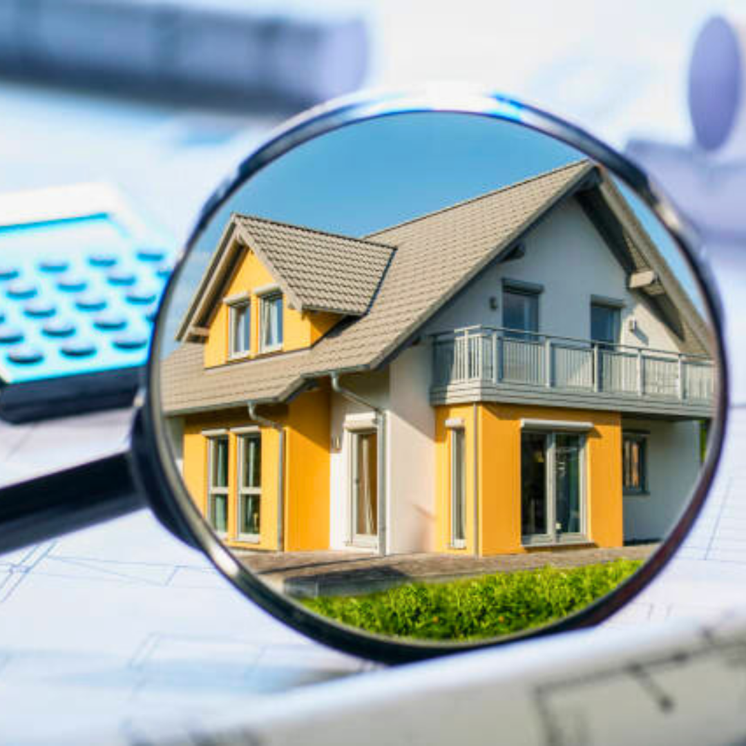 House magnified on blueprints with a calculator, highlighting property assessment.