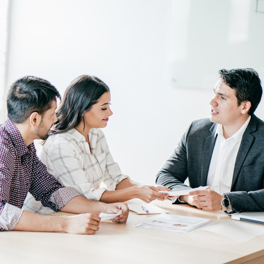 Couple reviewing documents with a professional in an office setting.