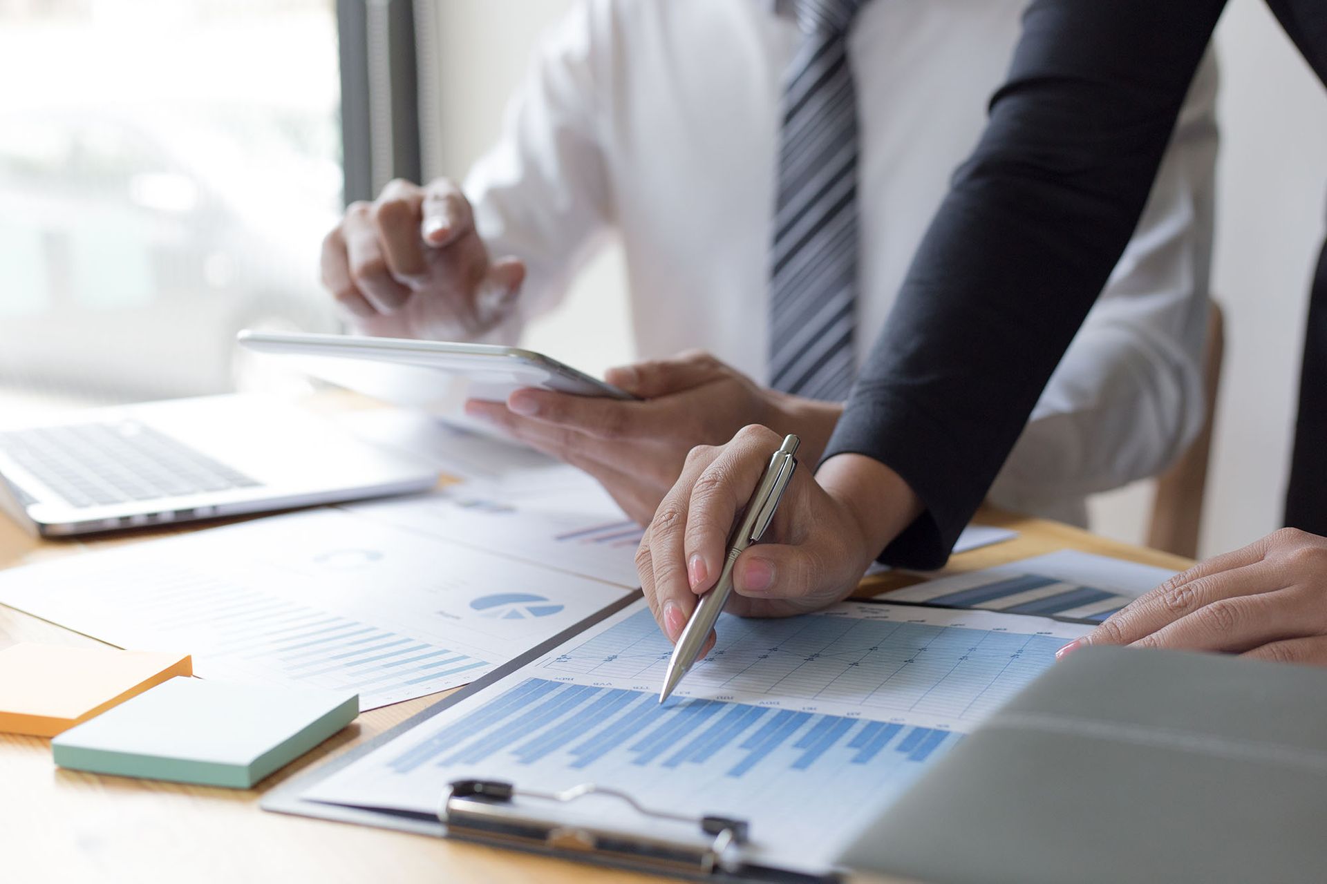 Two people reviewing financial data and charts at an office desk.