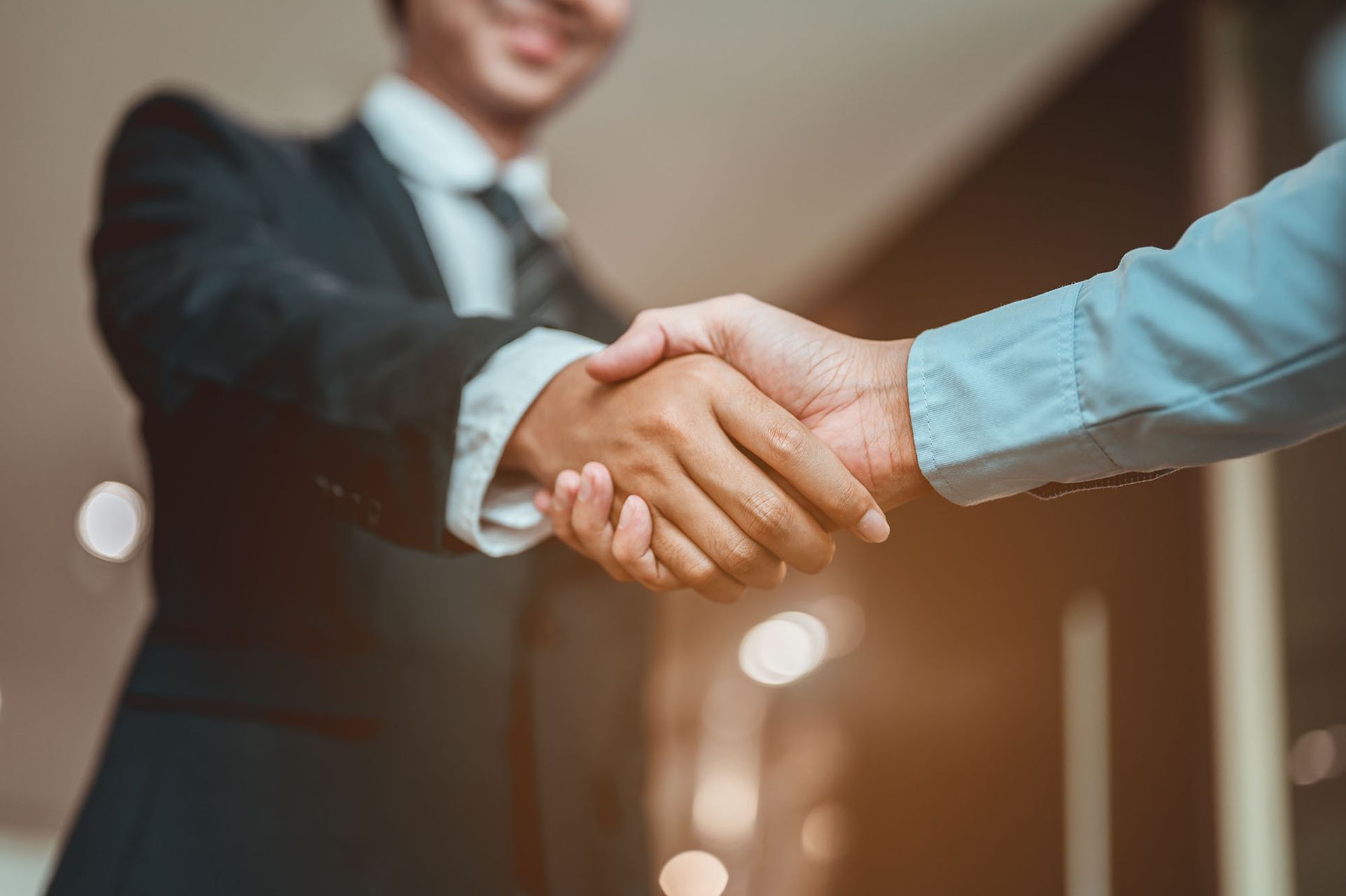 Two business people shaking hands in a professional setting, symbolizing agreement.
