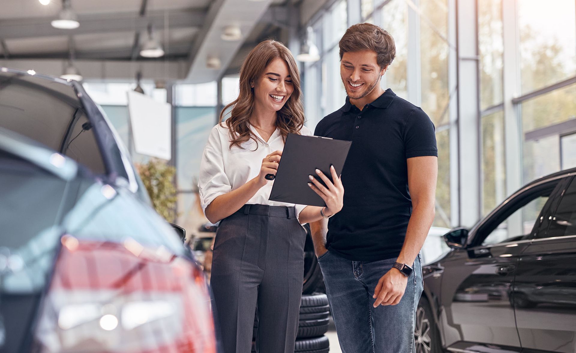 A car salesperson showing a man documents inside a car dealership.