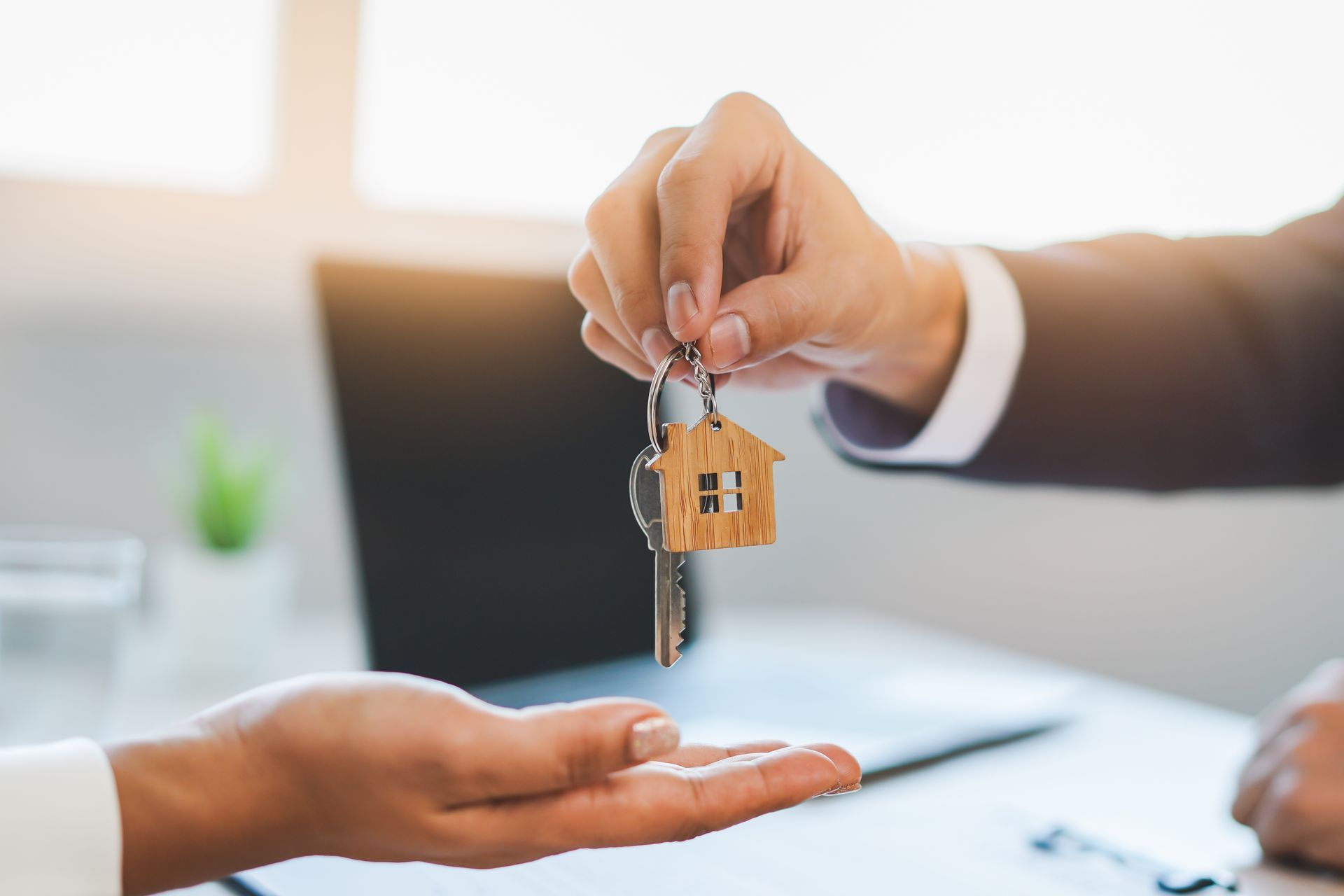 Close-up of a realtor's hand giving the house keys to a first-time home buyer.