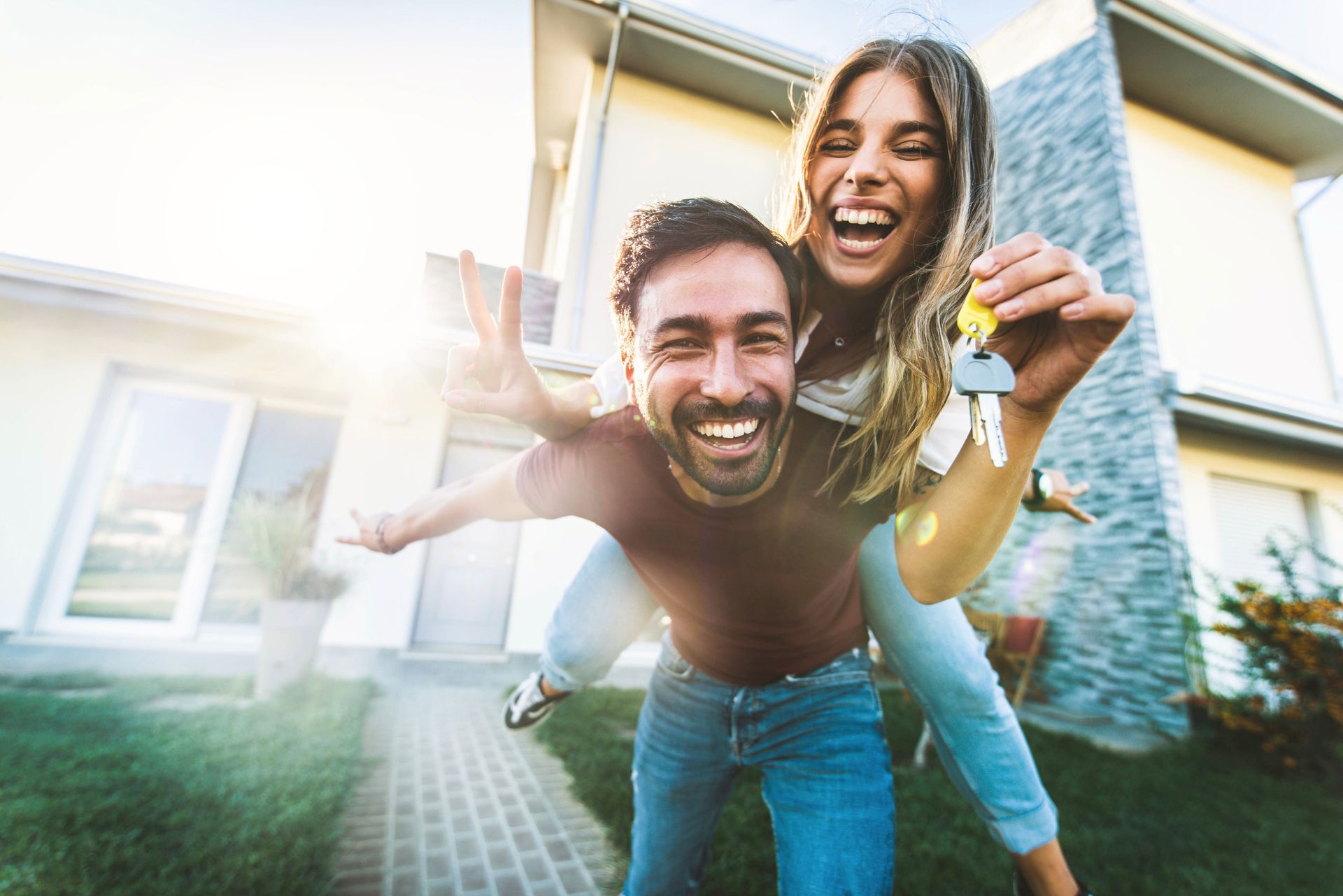 A happy young couple holding their keys in front of their new house.