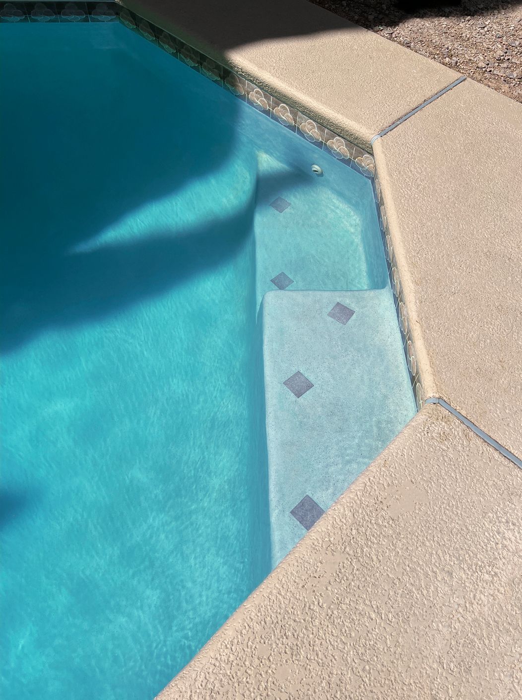 A close up of a swimming pool with blue water and steps.