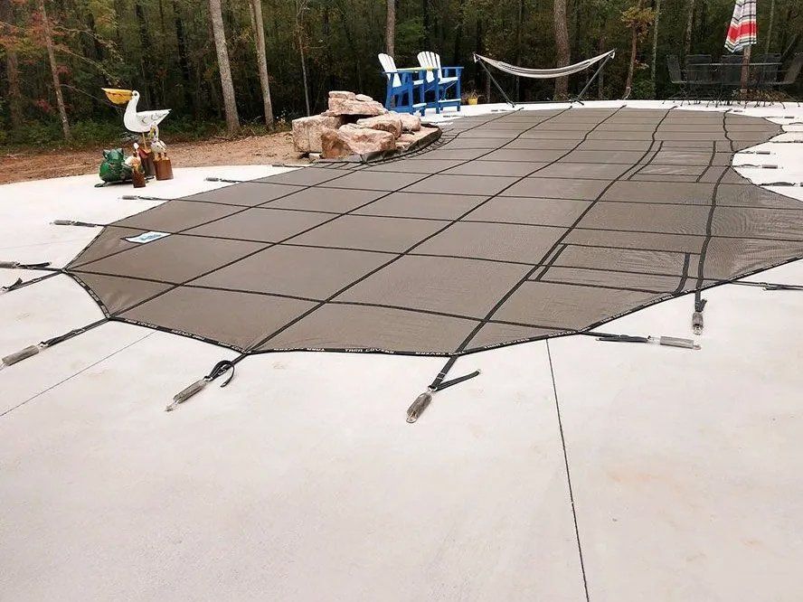 A large swimming pool is covered with a safety cover.