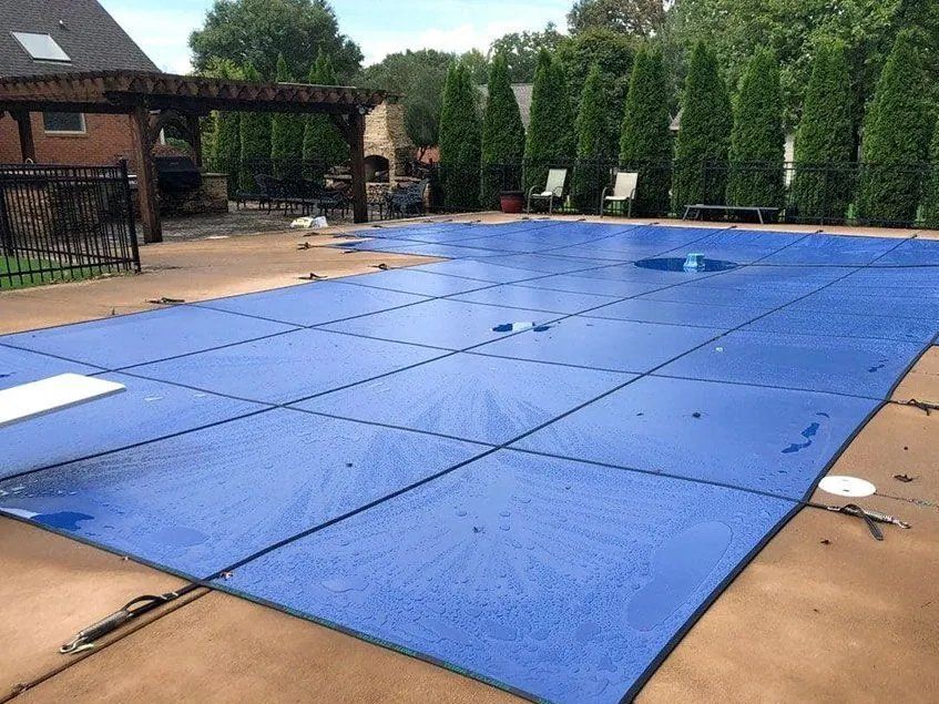 A large swimming pool with a blue cover on it.