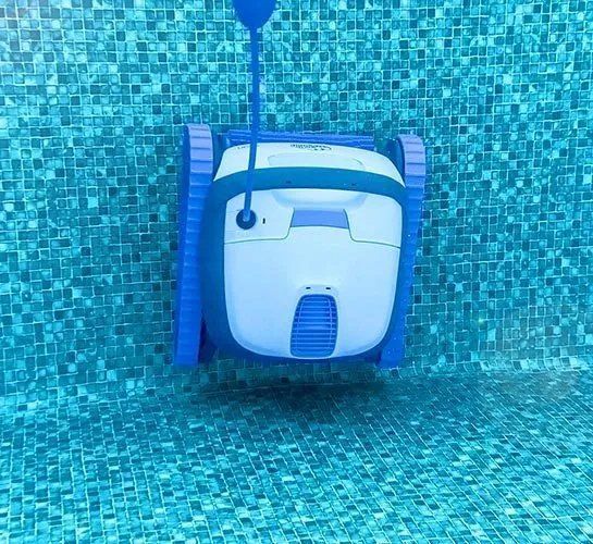 A blue and white robotic vacuum cleaner is floating in a swimming pool.