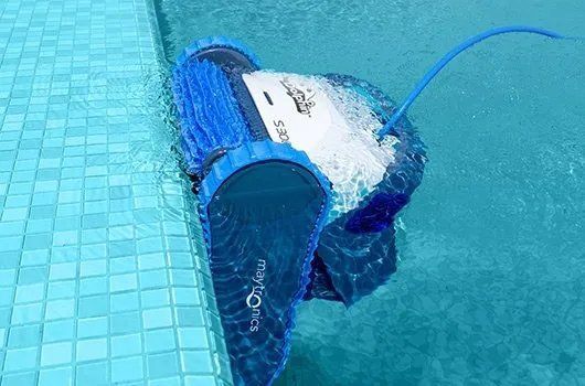 A robotic pool cleaner is floating on the edge of a swimming pool.
