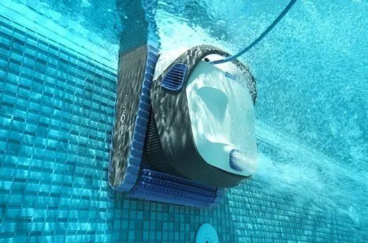 A robotic pool cleaner is swimming underwater in a swimming pool.