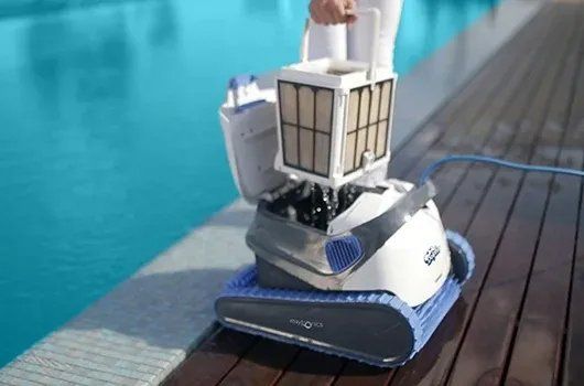 A person is cleaning a swimming pool with a robotic vacuum cleaner.