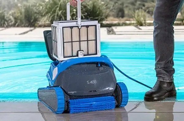 A person is standing next to a robotic pool cleaner.
