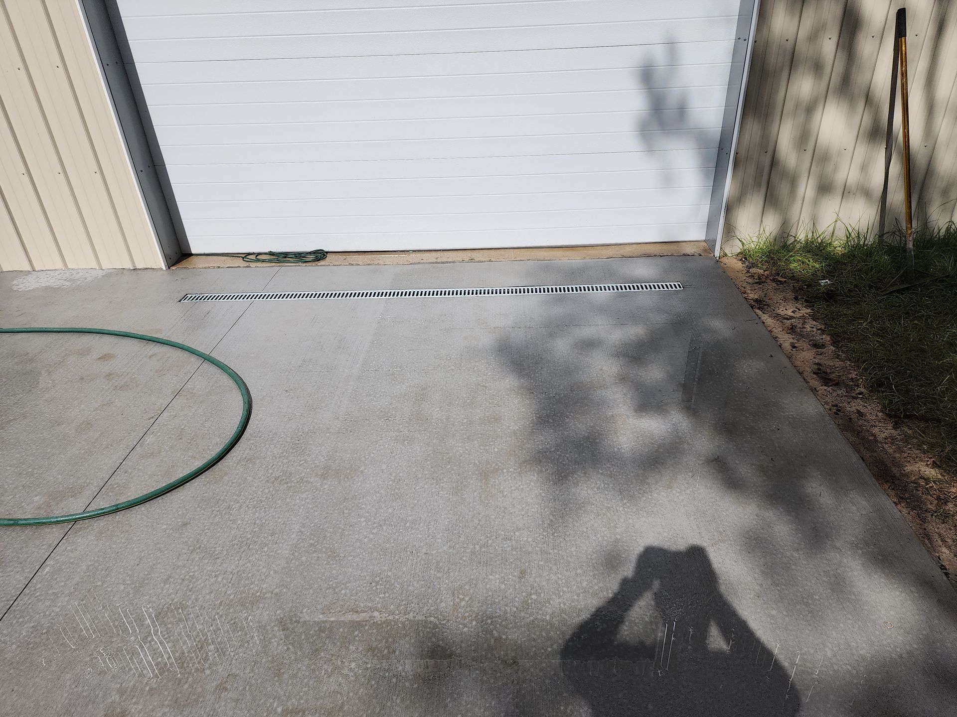 A shadow of a person is cast on a driveway next to a garage door.