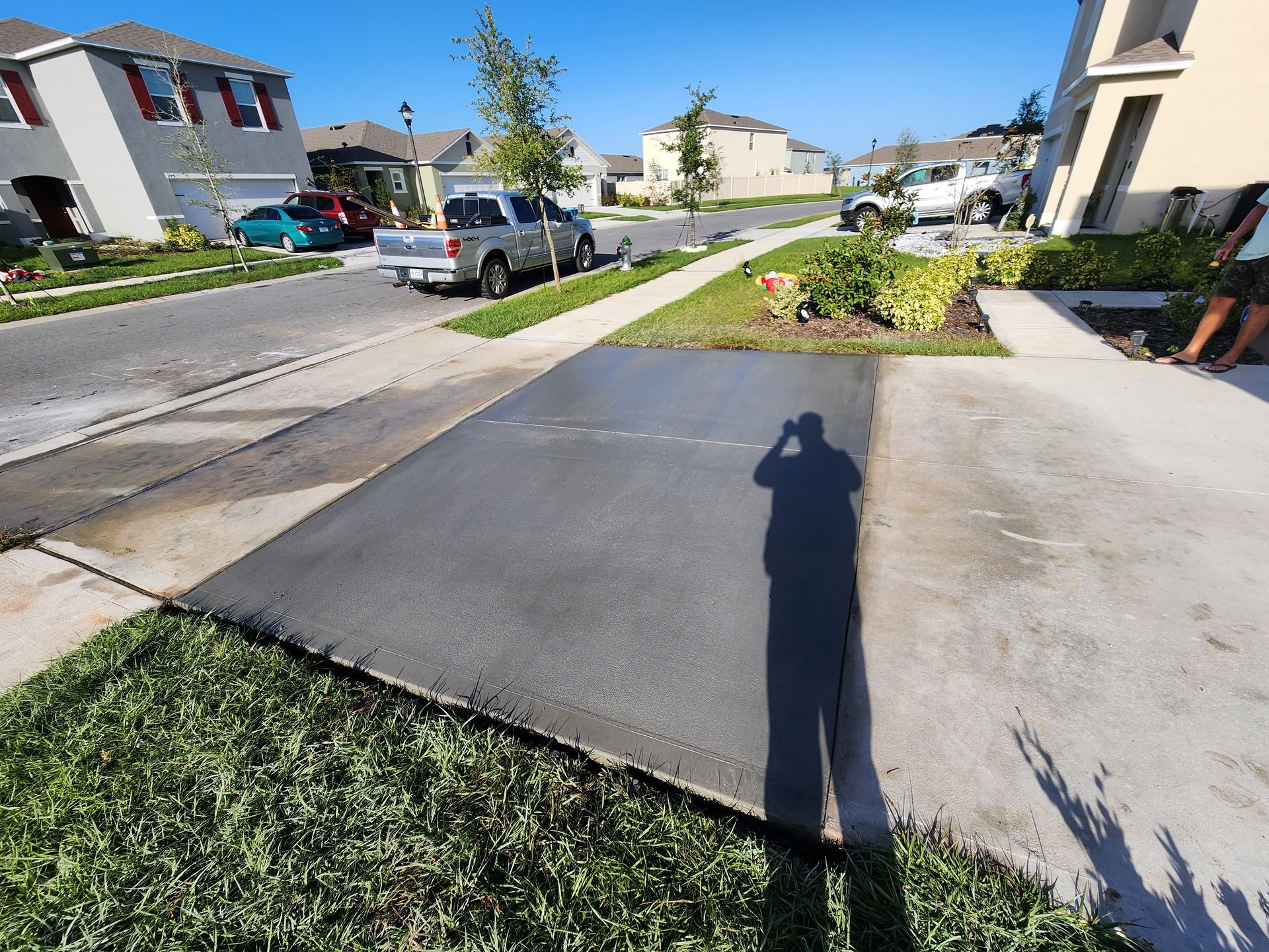 A shadow of a person is cast on a concrete driveway.