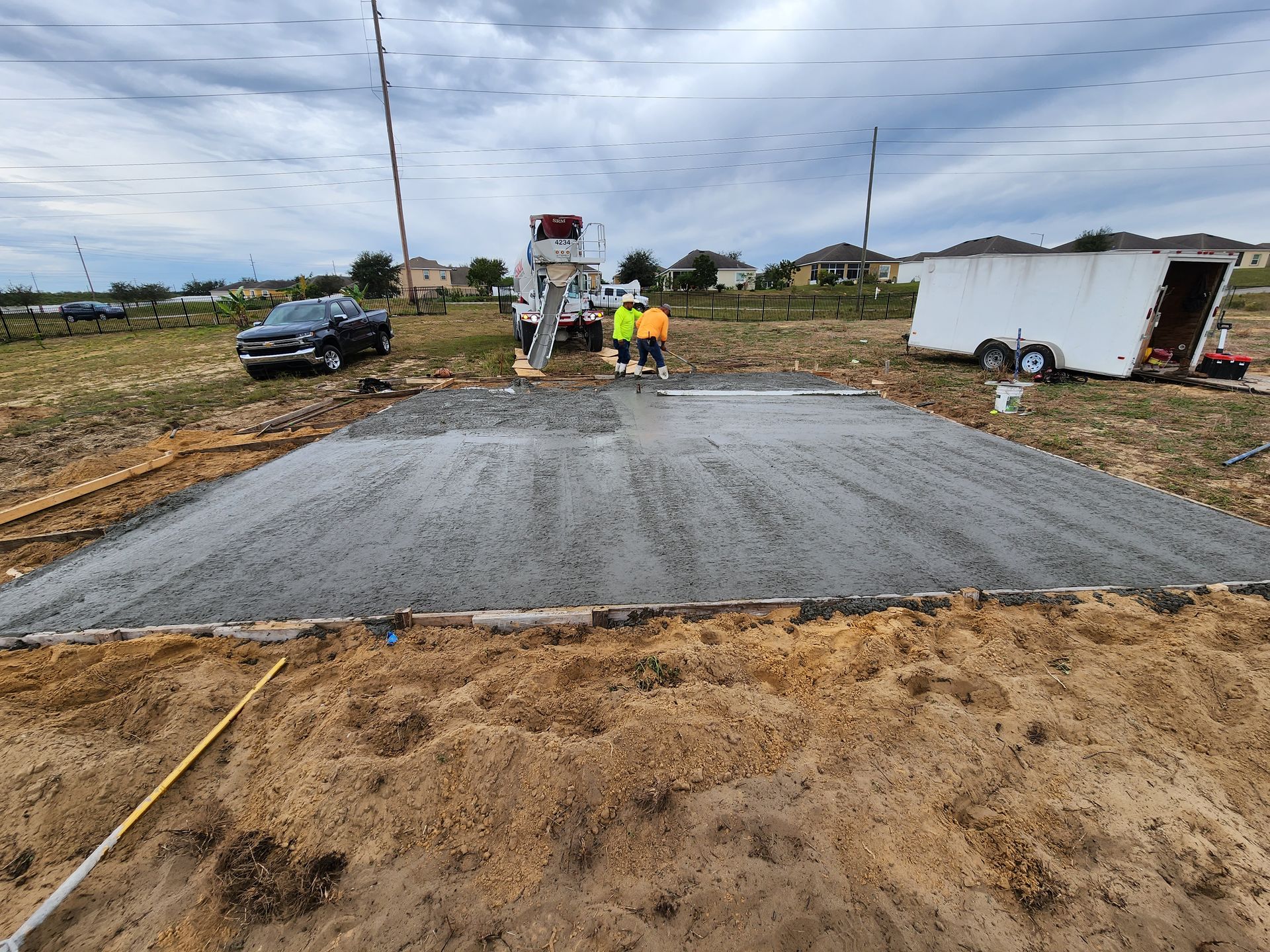 A concrete slab is being poured on a dirt field.