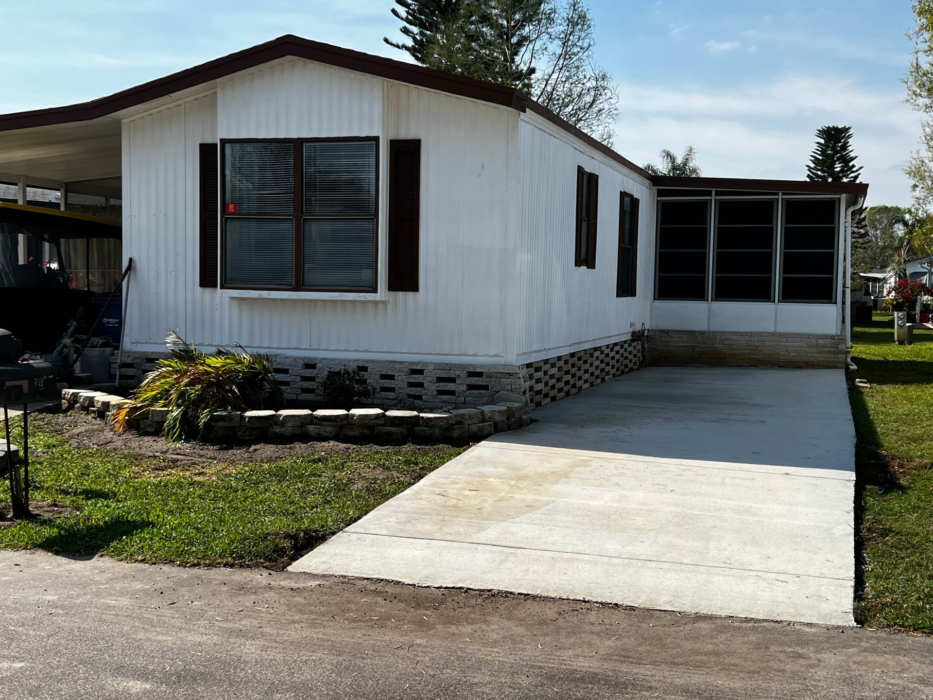 A white mobile home with a concrete driveway in front of it