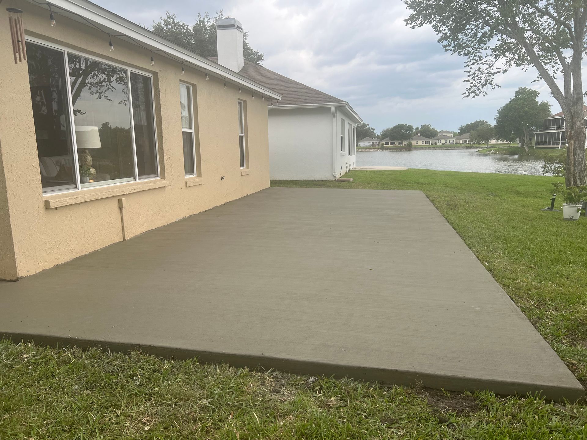 A concrete patio in front of a house with a lake in the background.