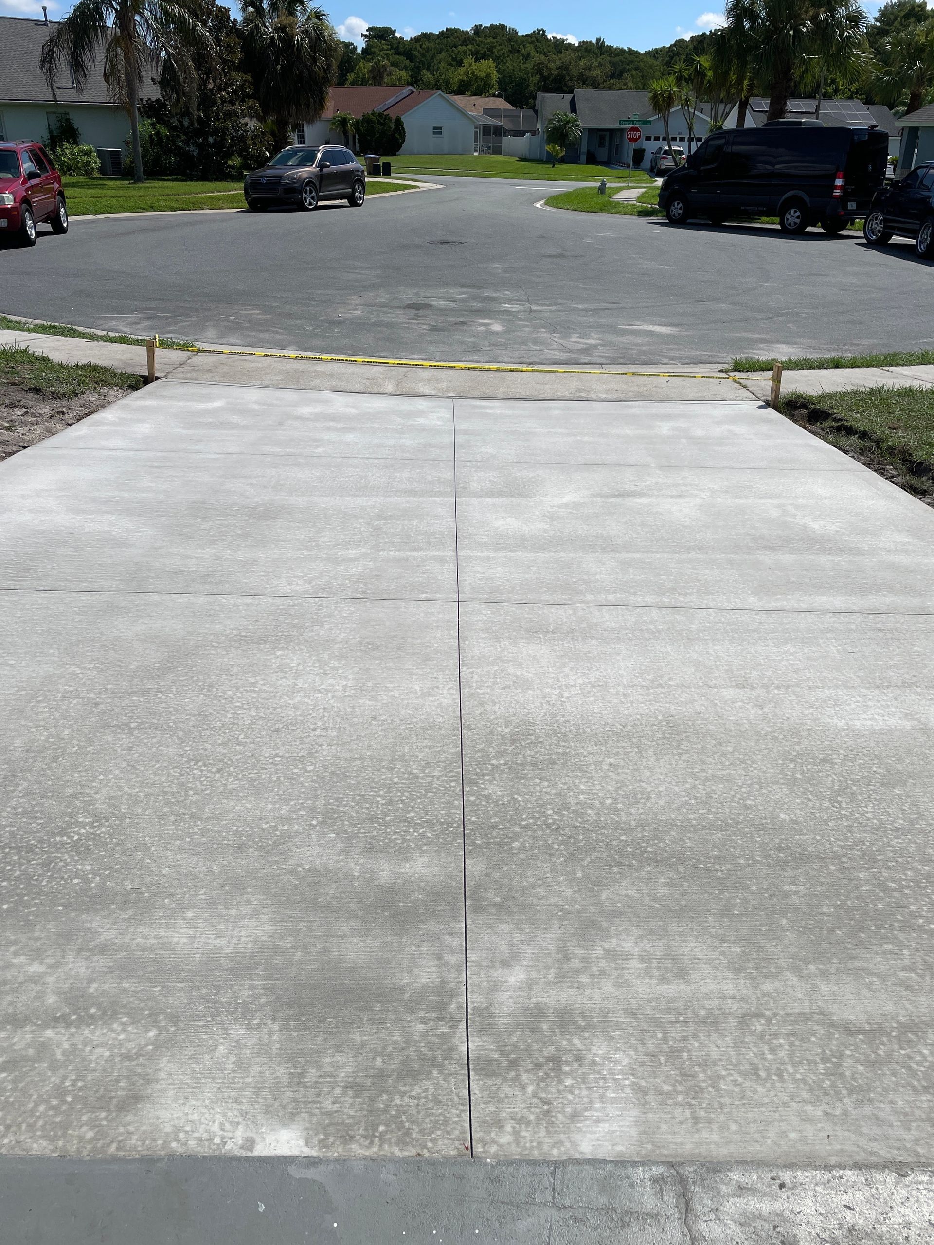 A concrete driveway with cars parked on the side of it