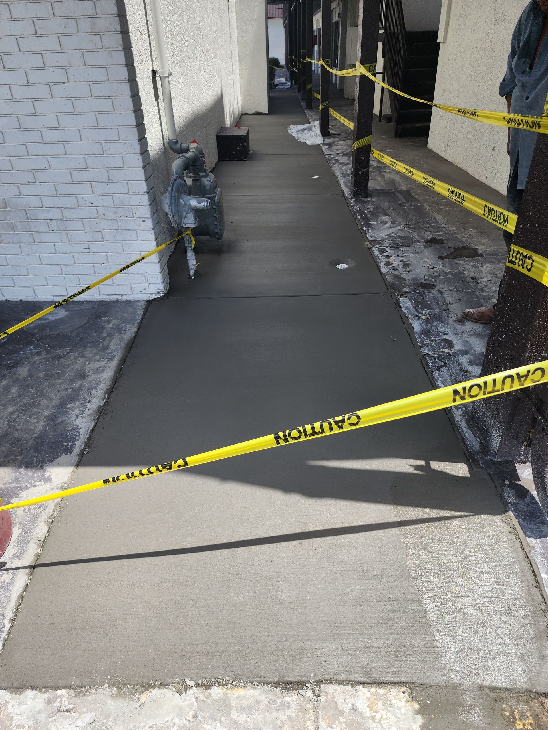A person is standing on a sidewalk with yellow tape.
