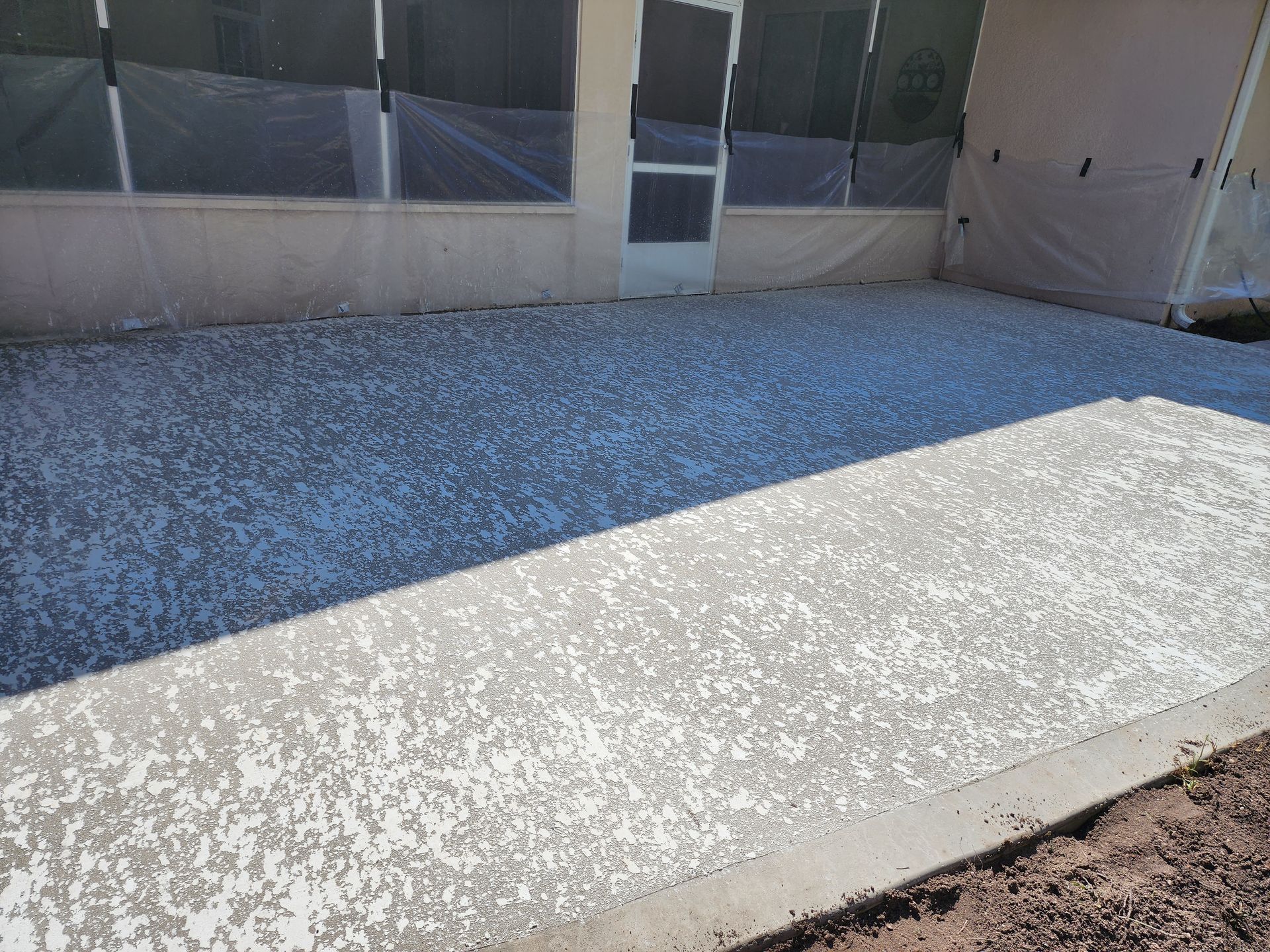 A patio with a concrete walkway and a sliding glass door.