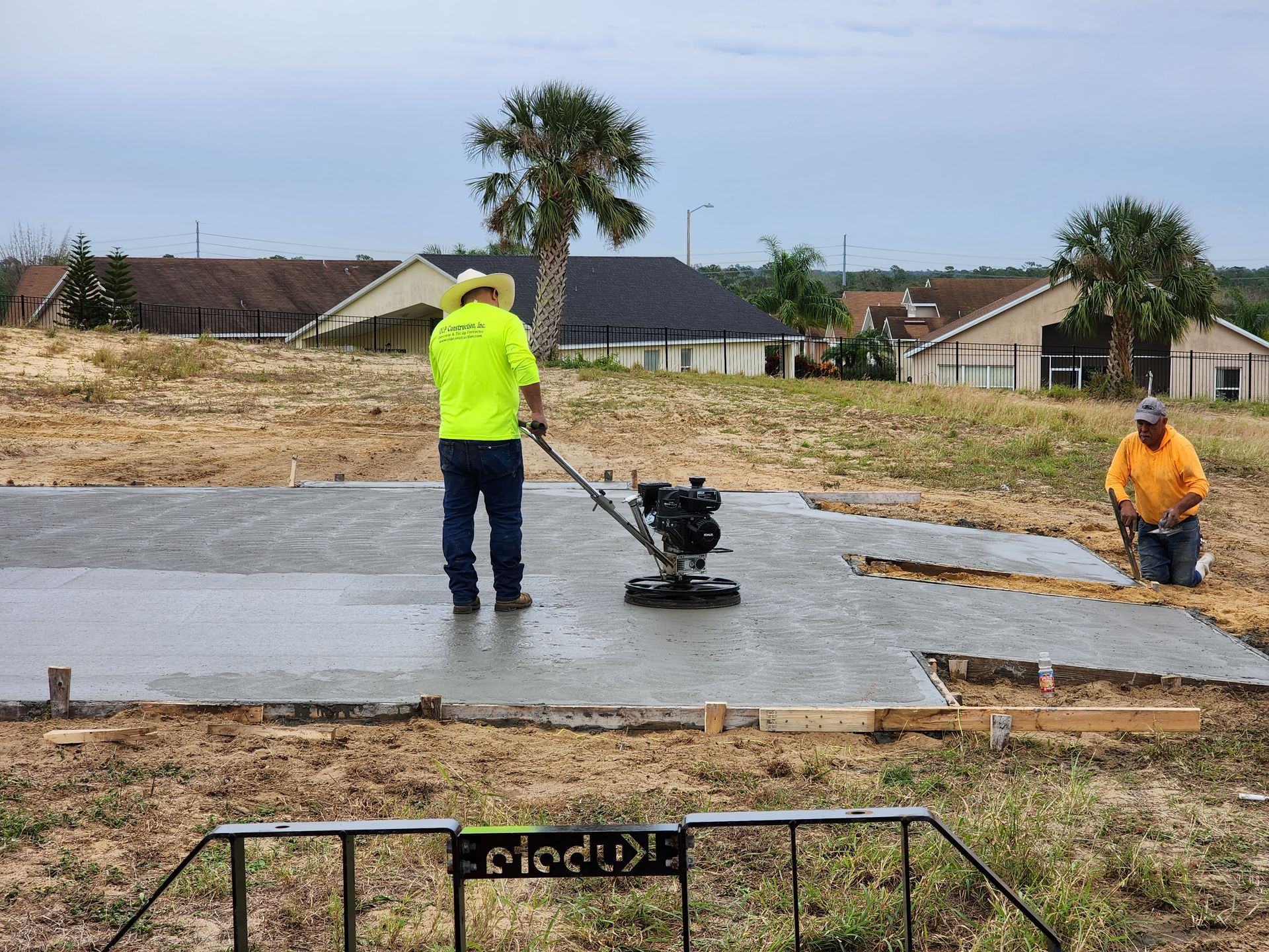 Two men are working on a concrete slab in a field.