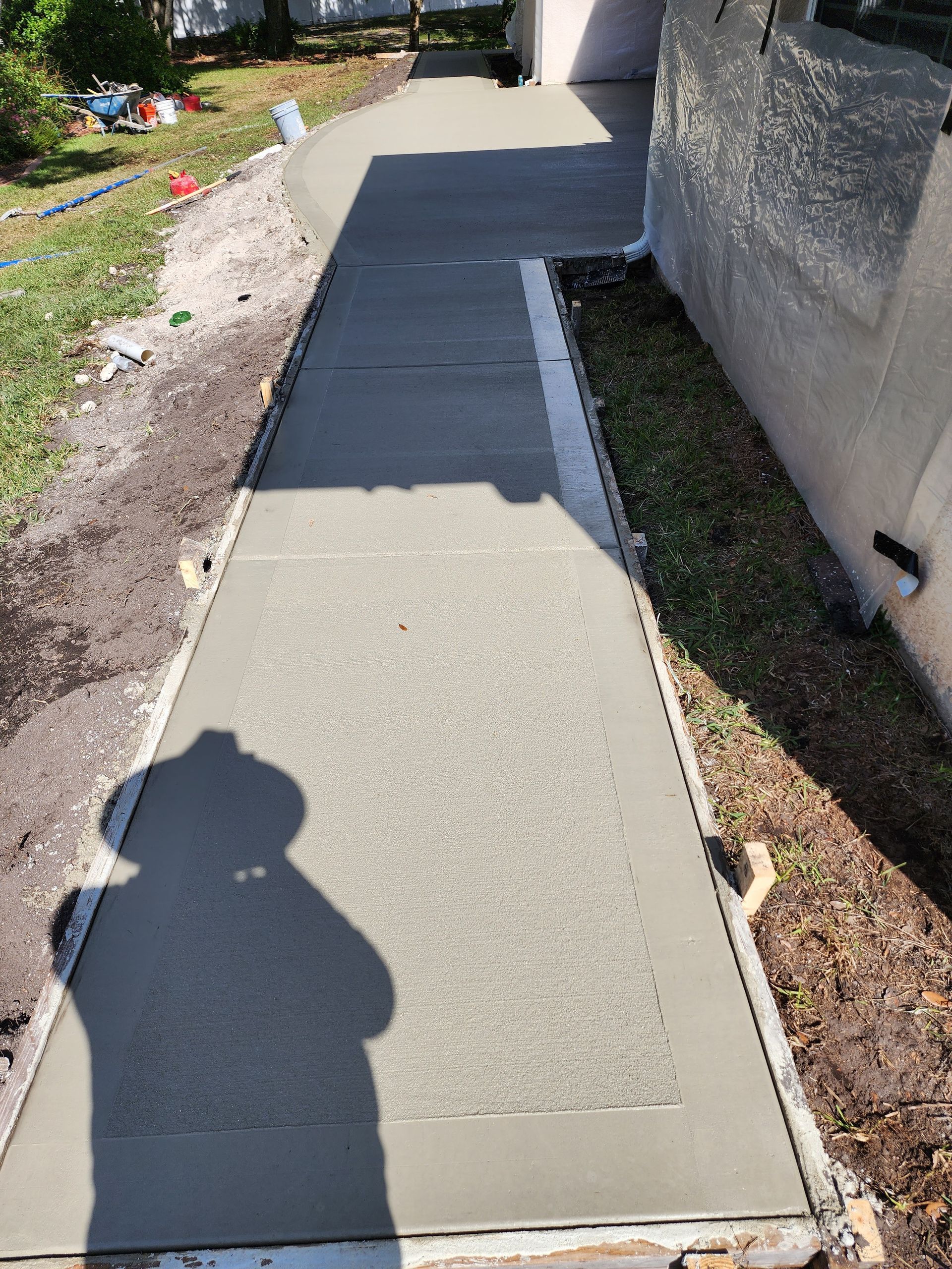 A shadow of a person is cast on a concrete walkway.