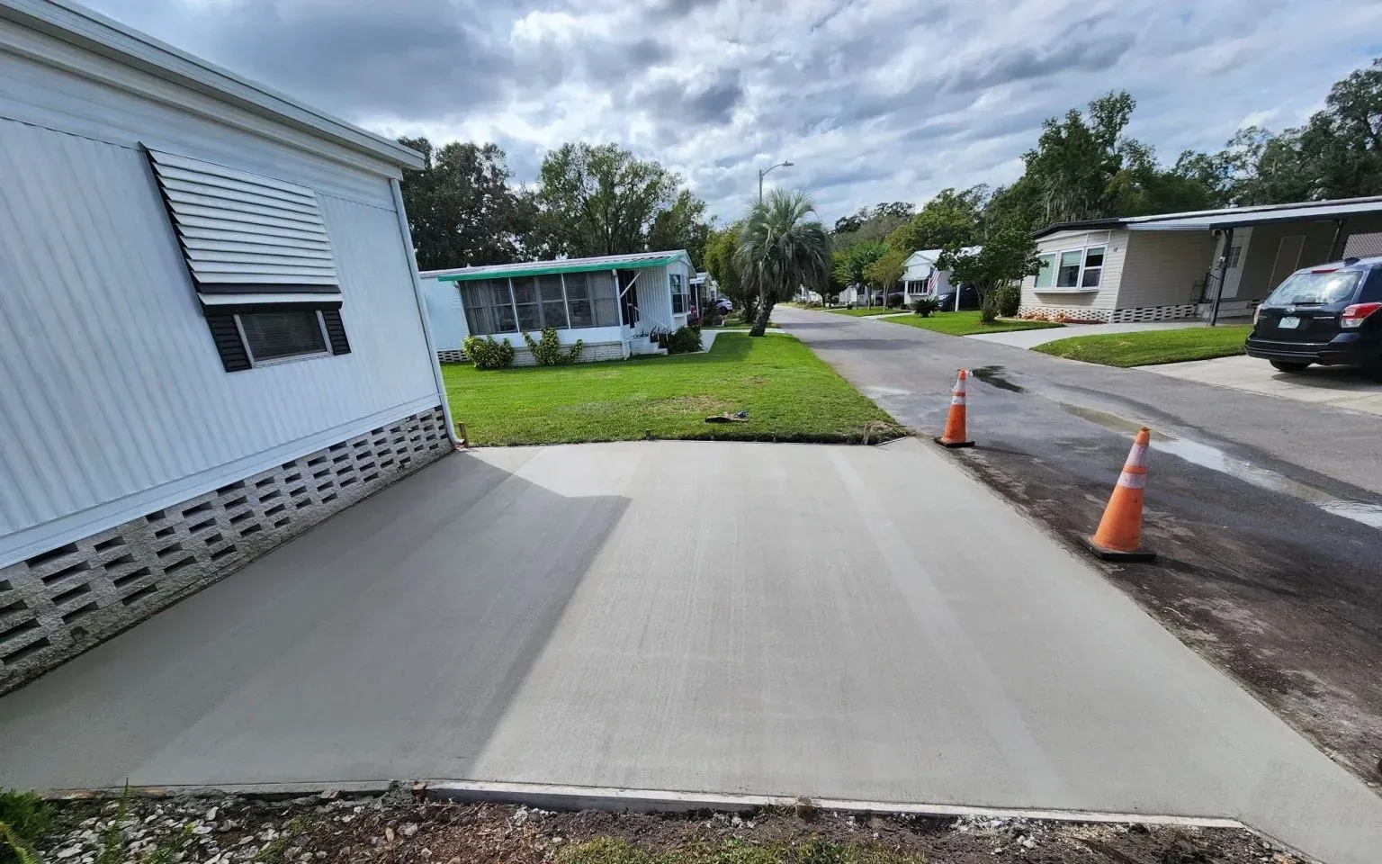 A concrete driveway is being built in front of a mobile home in a mobile home park.