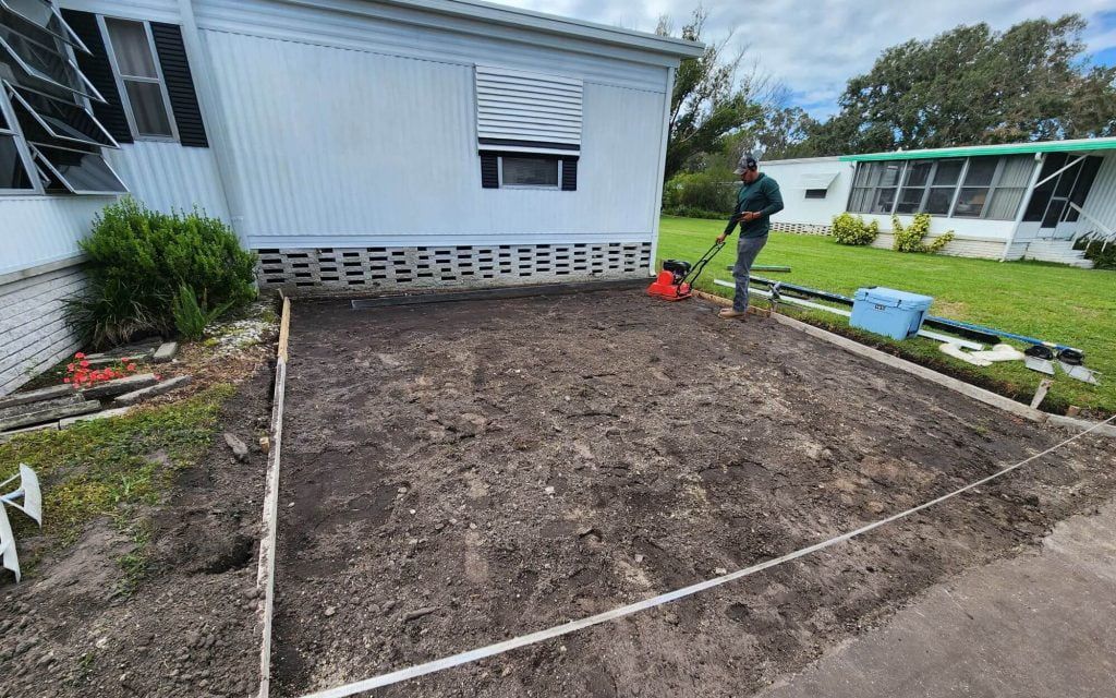 A man is digging a hole in front of a mobile home.