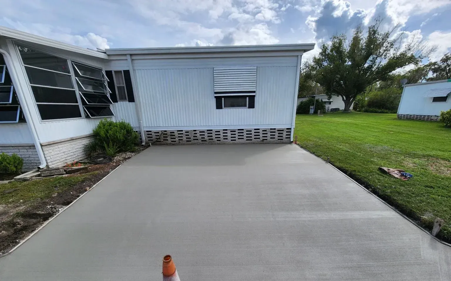 A mobile home with a concrete driveway in front of it.